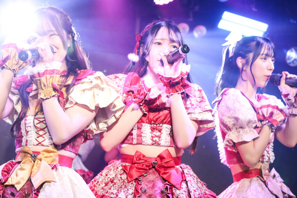 embellir(あんべりー)をライブ中に撮影した写真。
左から泡沫あおい(うたかたあおい)ちゃん、遥乃ももか(はるのももか)ちゃん、水野ひなた(みずのひなた)ちゃんが、横並びでマイクを構えて歌唱している。
2025年12月30日GOTANDA G3　FREE BOMBERにて撮影