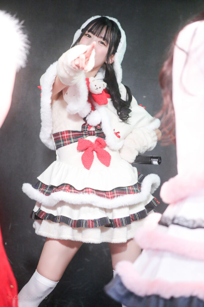 embellir(あんべりー)の水野ひなた(みずのひなた)ちゃんをライブ中に撮影した写真。
ゆきんこ衣装を着ている。こちらを真っ直ぐ見つめながら指さしてくれている。
2025年12月25日GOTANDA G3　冠Fes Xmas SP!にて撮影。