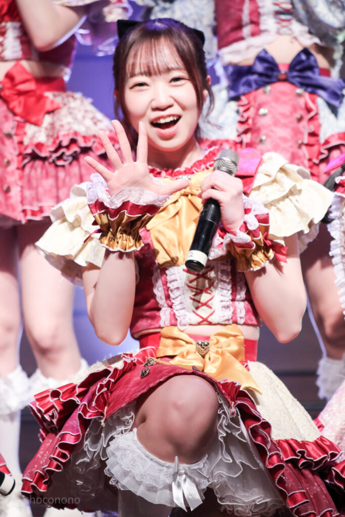 embellir(あんべりー)の泡沫あおい(うたかたあおい)ちゃんをライブ中に撮影した写真。
手の平を見せて「数字の5」を表現。5Daysライブの折り返しの日だったので、その5だったと思われる。
2025年12月29日時事通信ホール　ヴェルサウンドにて撮影。