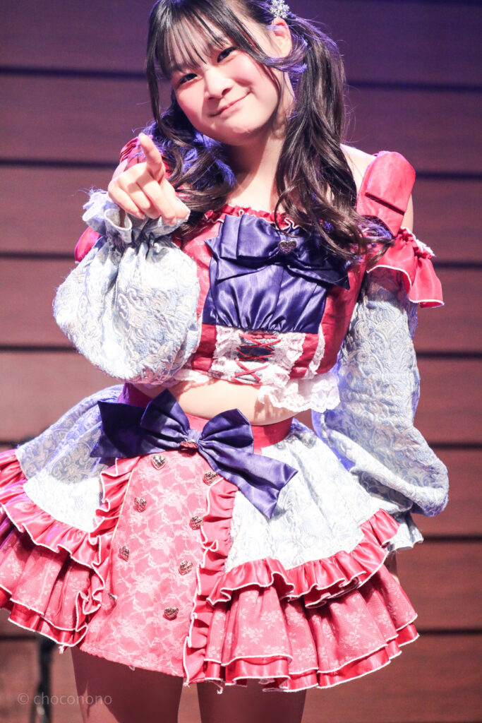 embellir(あんべりー)の恋羽あゆう(こはねあゆう)ちゃんをライブ中に撮影した写真。
こちらを見つめて指差しながら微笑んでくれている。
2025年12月29日時事通信ホール　ヴェルサウンドにて撮影。