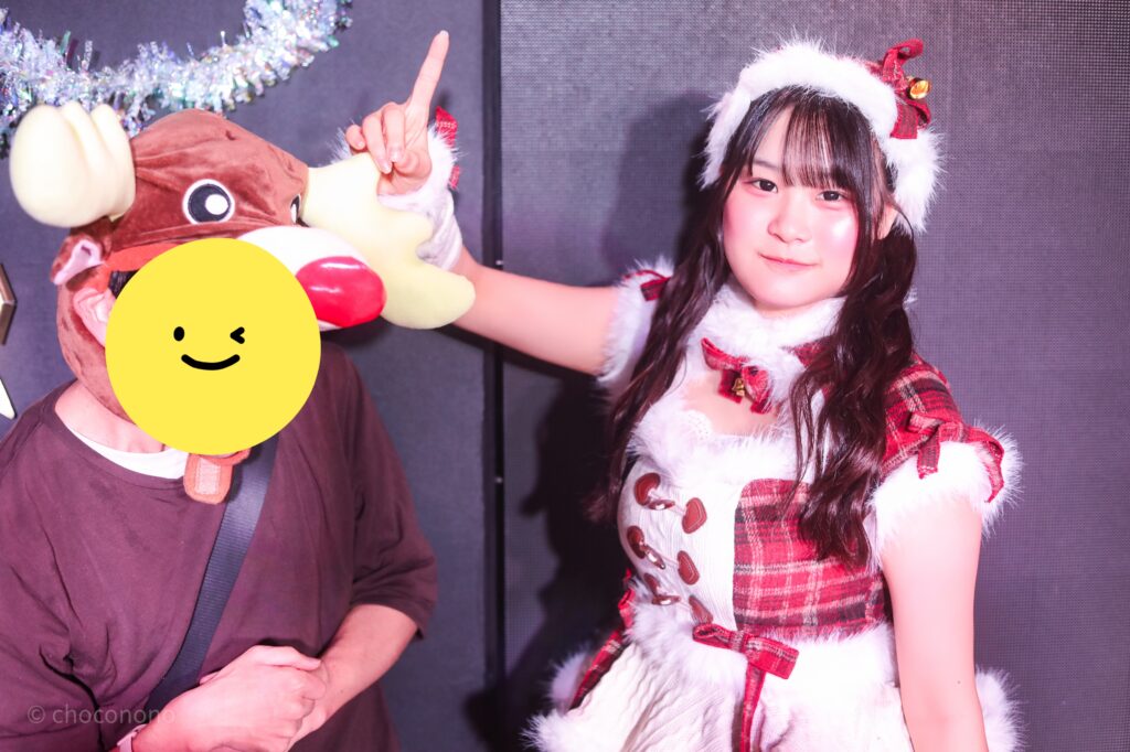 embellir(あんべりー)の恋羽あゆう(こはねあゆう)ちゃんと特典会で撮ってもらったツーショット写真。亜夕ちゃんはふわふわがたくさんついたサンタ衣装。私のトナカイ帽子の上に角を付けるようなポーズをしている。
2025年12月27日SHIBUYA ONE5 embellir presents Christmas Liveにて撮影。