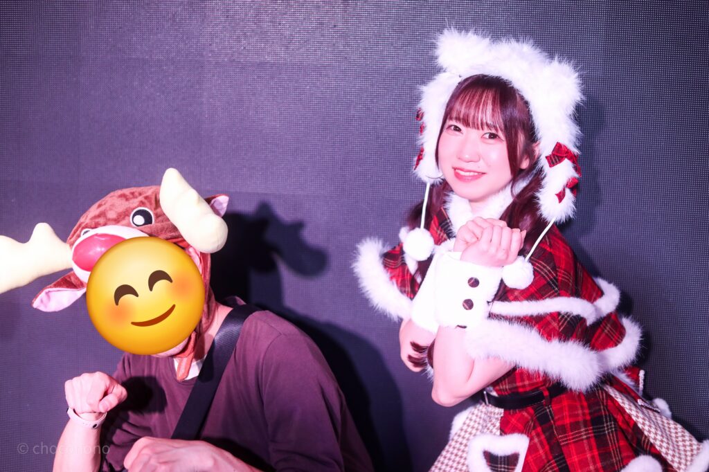 embellir(あんべりー)の泡沫あおい(うたかたあおい)ちゃんと特典会で撮ってもらったツーショット写真。あおいちゃんはふわふわのたくさん付いた猫サンタ衣装で、プレゼント袋を担ぎながらトナカイ姿の私が引くそりに乗っているジェスチャー。
2025年12月27日SHIBUYA ONE5 embellir presents Christmas Liveにて撮影。