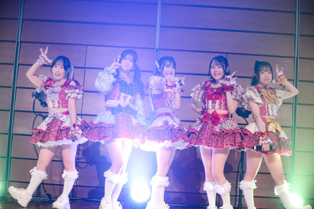 embellir(あんべりー)をライブ中に撮影した写真。
フツーに奇跡!!のラストのフォーメーション。横一列に並びそれぞれがポーズを決めている。左から甘夏あも(あまなつあも)ちゃん、恋羽あゆう(こはねあゆう)ちゃん、水野ひなた(みずのひなた)ちゃん、遥乃ももか(はるのももか)ちゃん、泡沫あおい(うたかたあおい)ちゃん。
2025年12月29日時事通信ホール　ヴェルサウンドにて撮影。