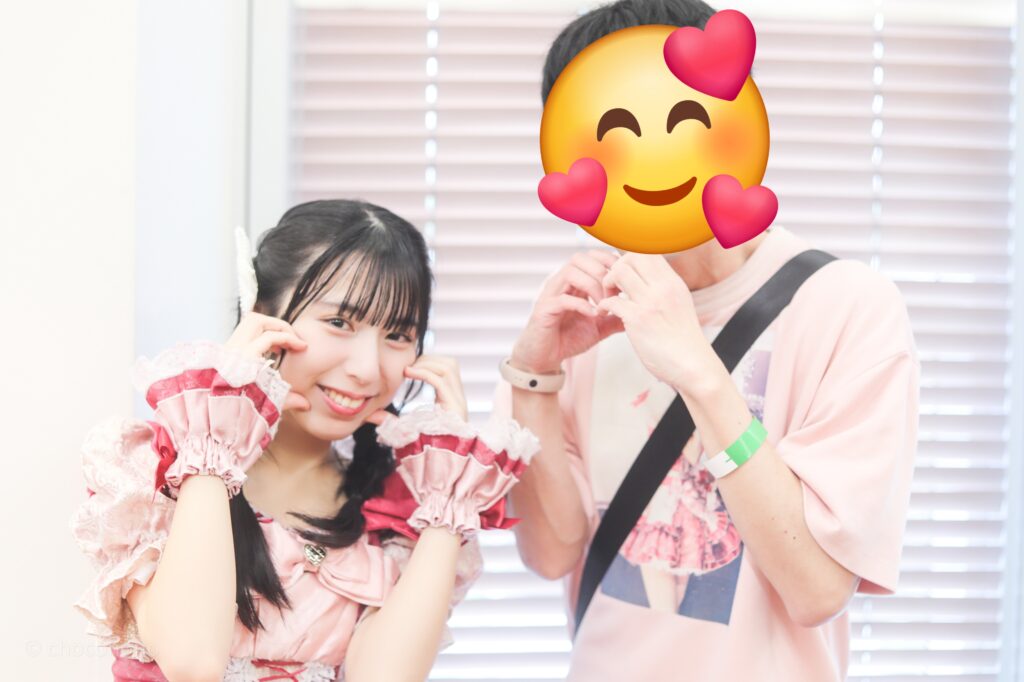 embellir(あんべりー)の水野ひなた(みずのひなた)ちゃんと特典会で撮ってもらったツーショット写真。 二人でそれぞれハートを作るジェスチャーをしている。
 2025年12月29日　時事通信ホール　ヴェルサウンドにて撮影。