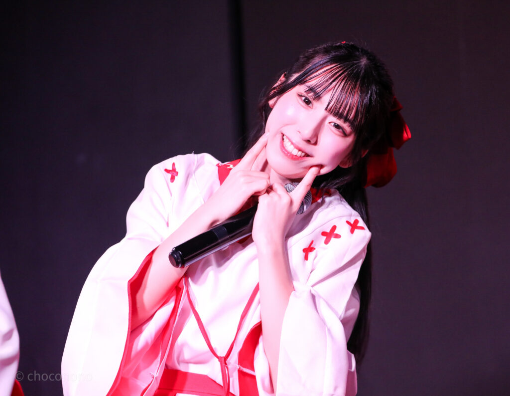 embellir(あんべりー)の水野ひなた(みずのひなた)ちゃんをライブ中に撮影した写真。
巫女服を着ている。両側のほっぺたに指を当てて「にこーっ」と笑っている。天使。
 2026年1月4日SHIBUYA ONE5　新春ONE5LIVEにて撮影。