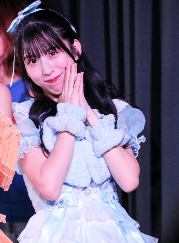 embellir(あんべりー)の水野ひなた(みずのひなた)ちゃんをライブ中に撮影した写真。
カメラを向けているのに気付いていたずらっぽく微笑んでいる。
2025年12月31日SHIBUYA ONE5　ONE5 SHUFFLE FESTIVALにて撮影。