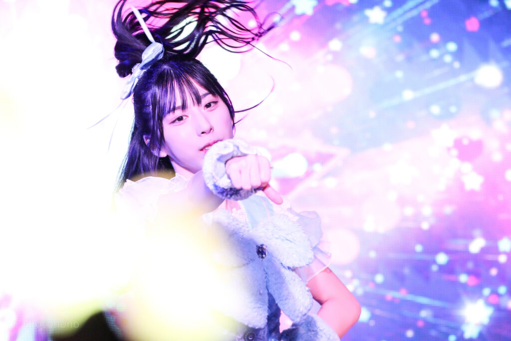 embellir(あんべりー)の水野ひなた(みずのひなた)ちゃんをライブ中に撮影した写真。
激しい動きに髪が靡いている。拳を前に突き出している。かっこいい。
2025年12月31日SHIBUYA ONE5　ONE5 SHUFFLE FESTIVALにて撮影。